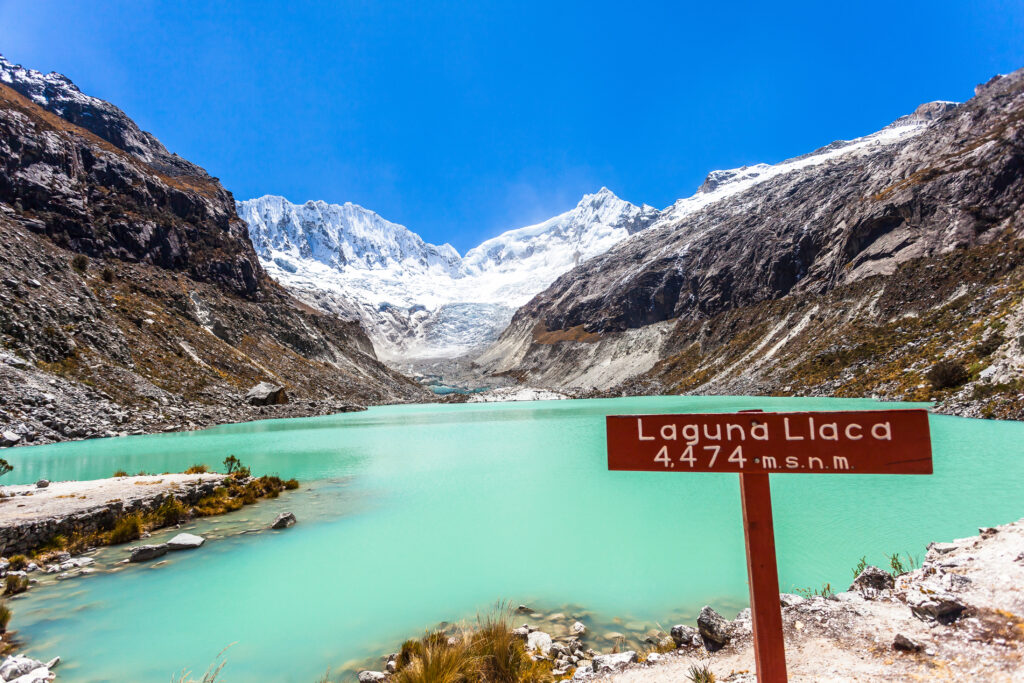 The greeny blue Llaca lagoon with the snowy peaks of Ocshapalpa and Ranrapalca mountains behind