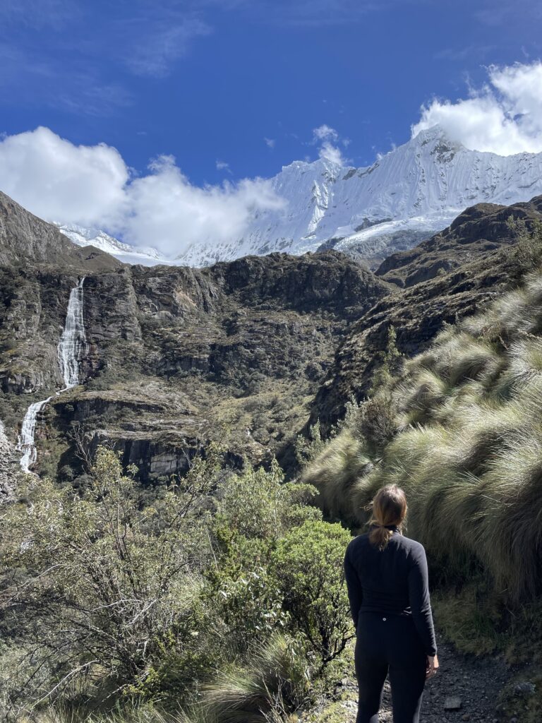 Megan looking out on mountains and a waterfall on the hike to Laguna 69