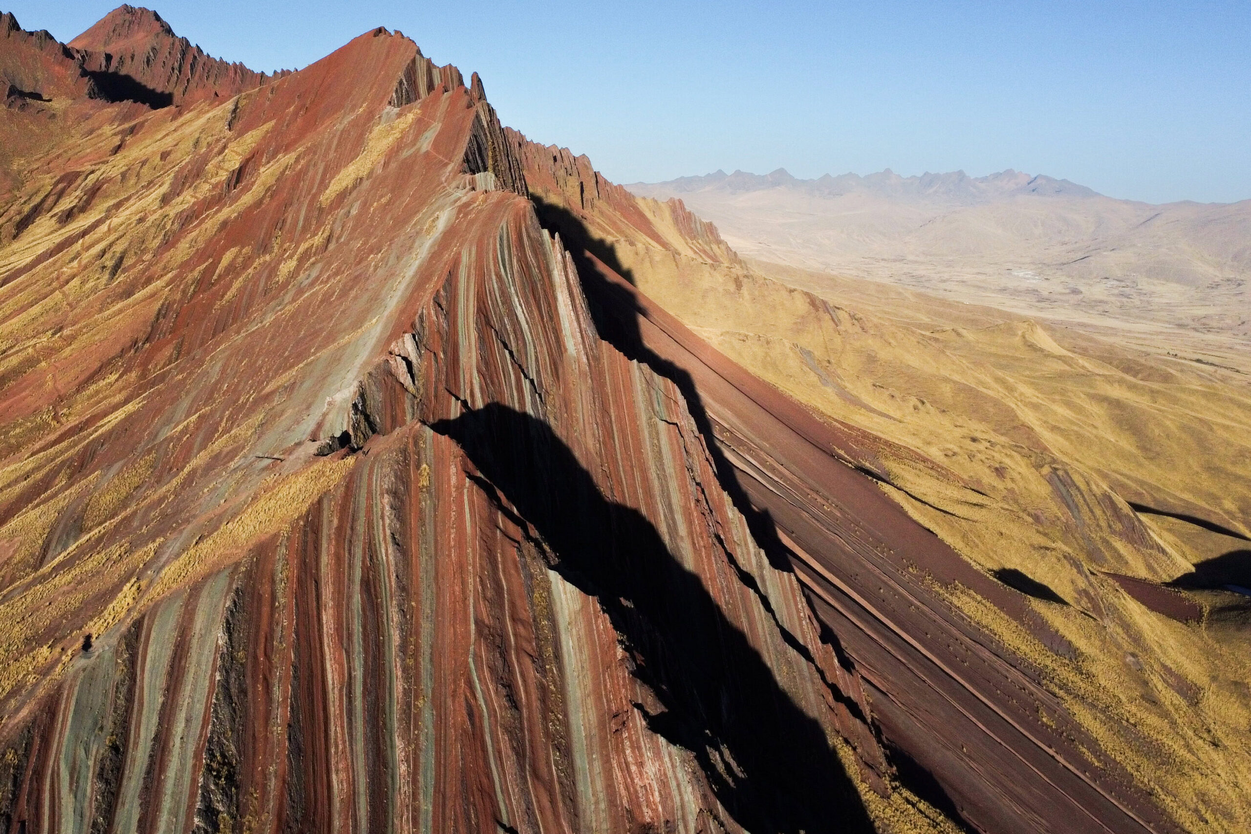 A drone photo showing a birdseye view of the jagged, sheer mountain sides of the colourful Pallay Punchu.