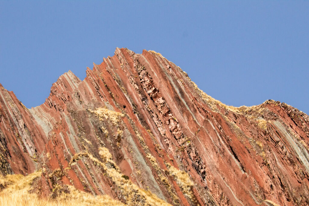 A close up of the jagged edges of Pallay Punchu Mountain striped with colours of red, pink and blue. 