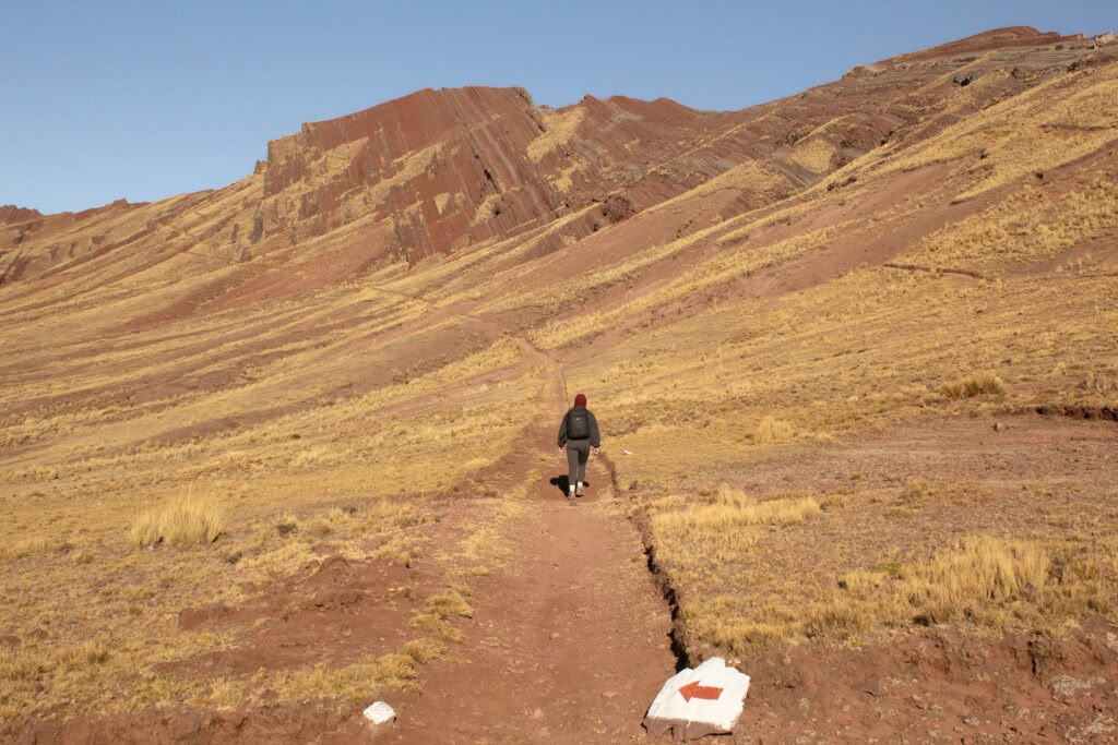 Megan at the start of the short loop to the Pallay Punchu viewpoint with a red arrow on a white background painted on a rock that is leading the way
