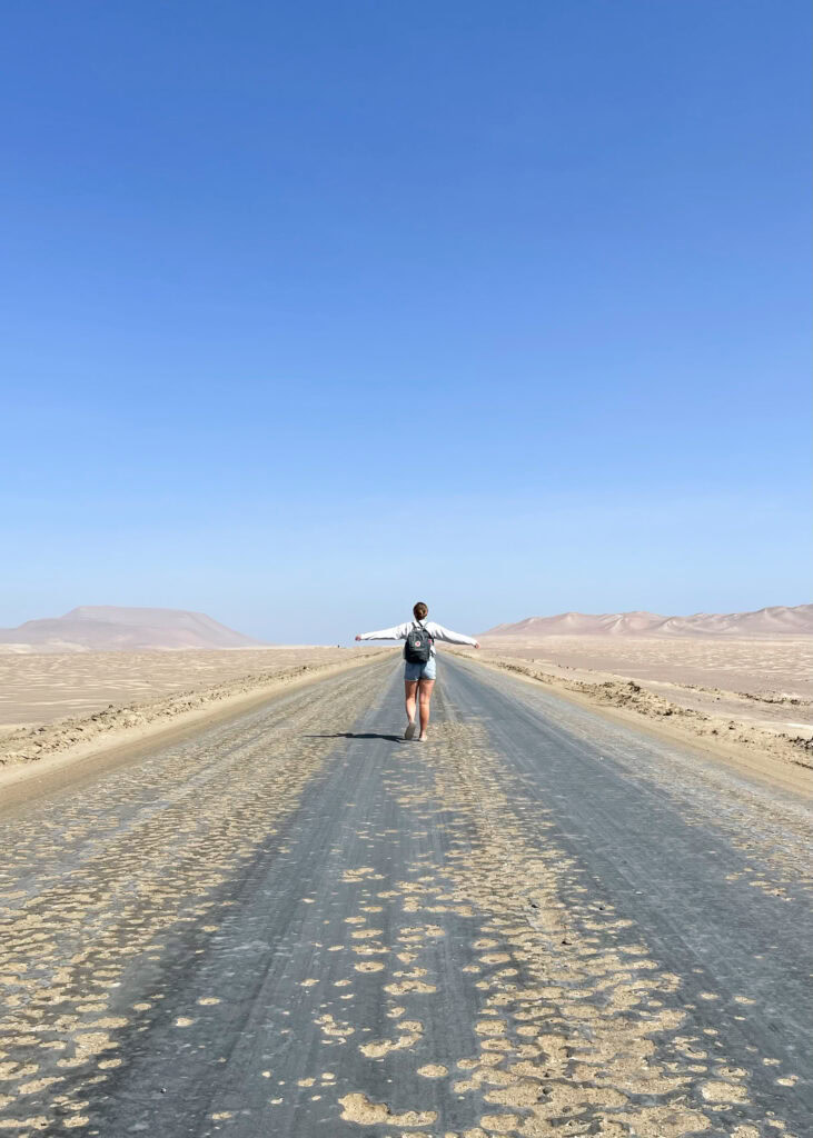 Megan walking along the 10 km road that leads from Paracas to Playa Supay with the arid desert on either side.