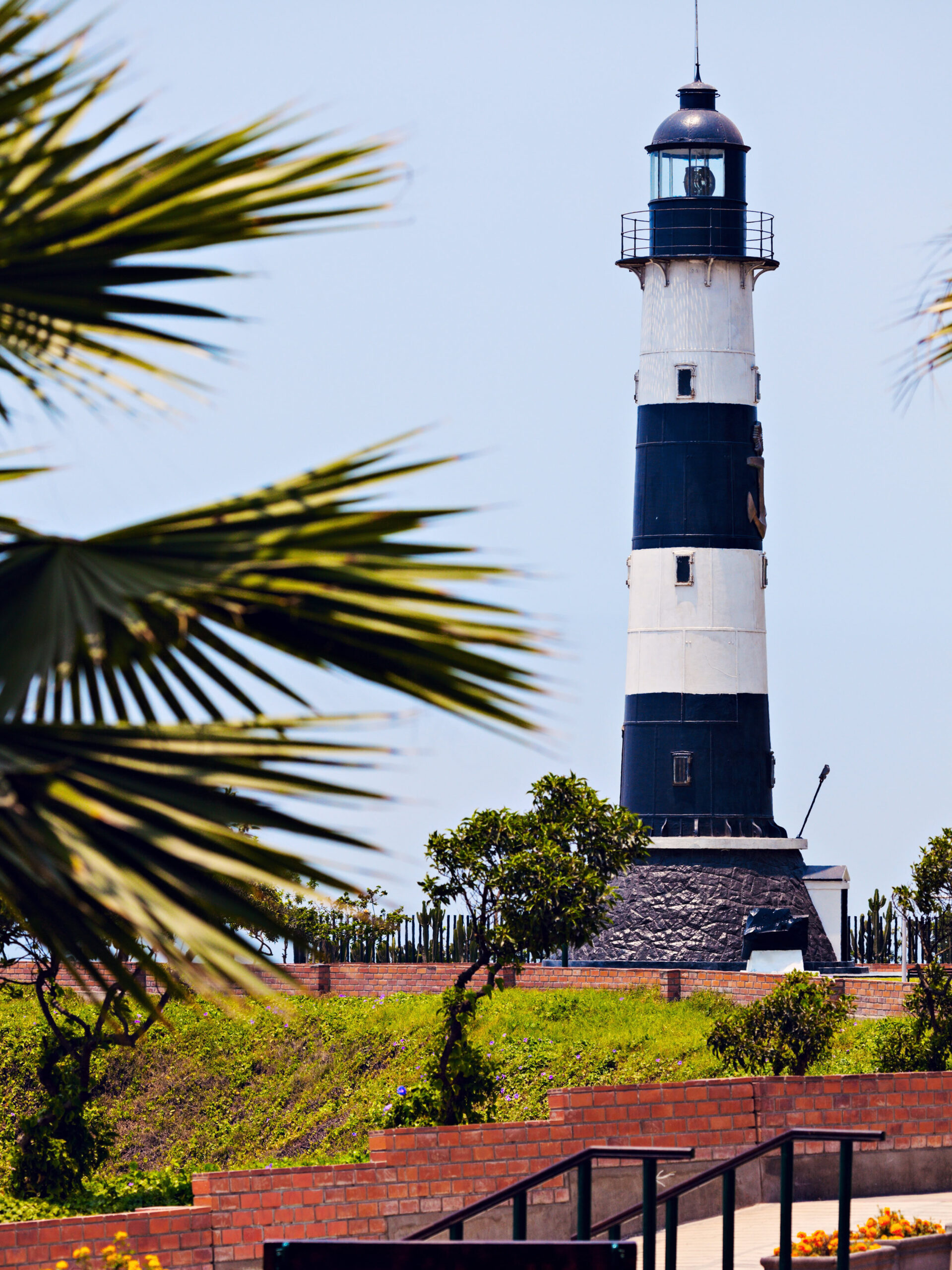 Black and white striped Miraflores lighthouse with a palm tree in the foreground