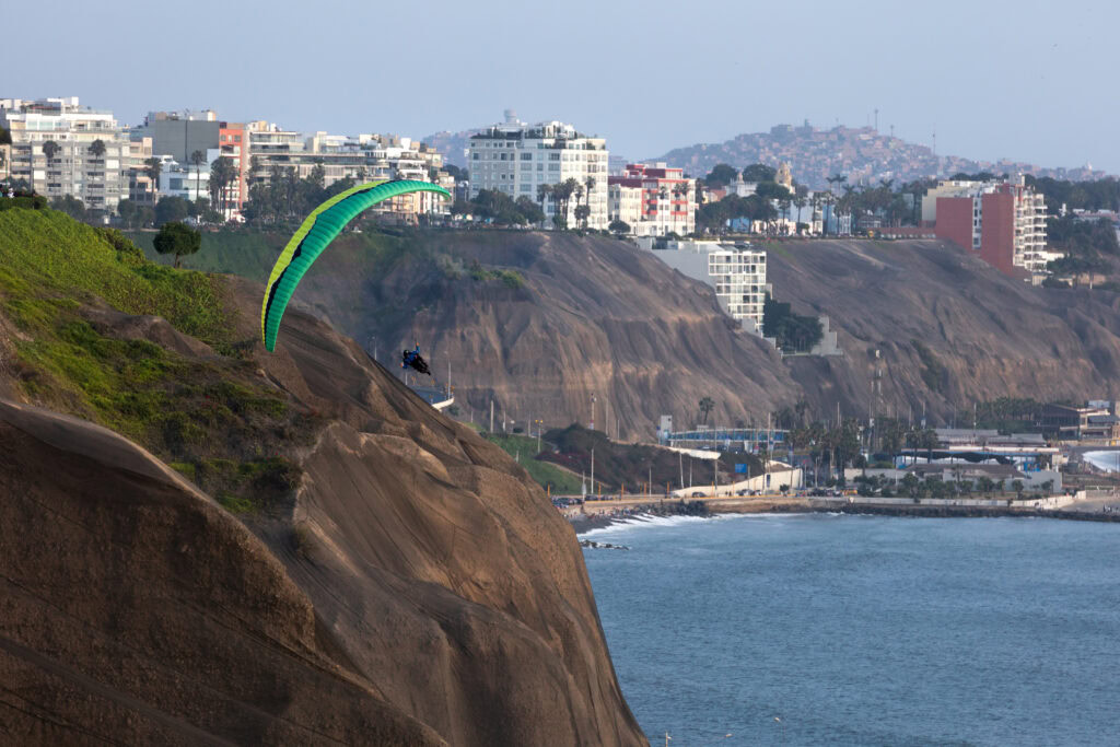 A person paragliding next to the cliffs of Costa Verde in Lima 