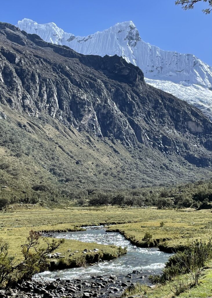 River flowing through the valley at the start of the Laguna 69 hike. Snow-capped mountains are looming in the background. 