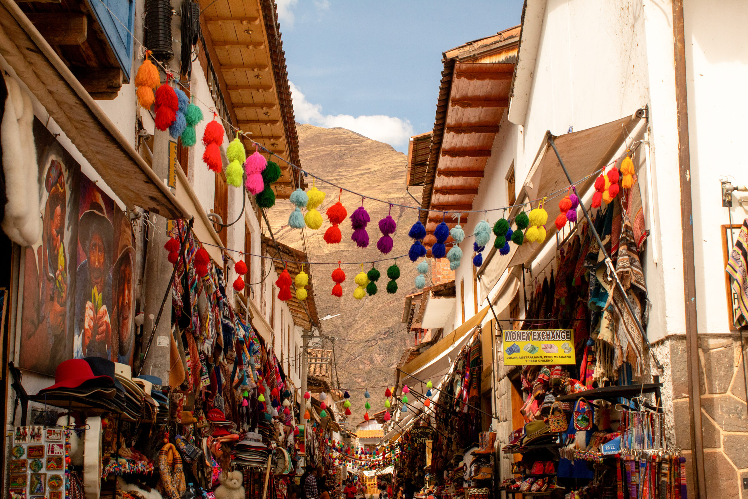 Colourful street off the edge of Pisac's plaza, with a variety of shops and strings of colourful tassels hanging between the colonial buildings. 